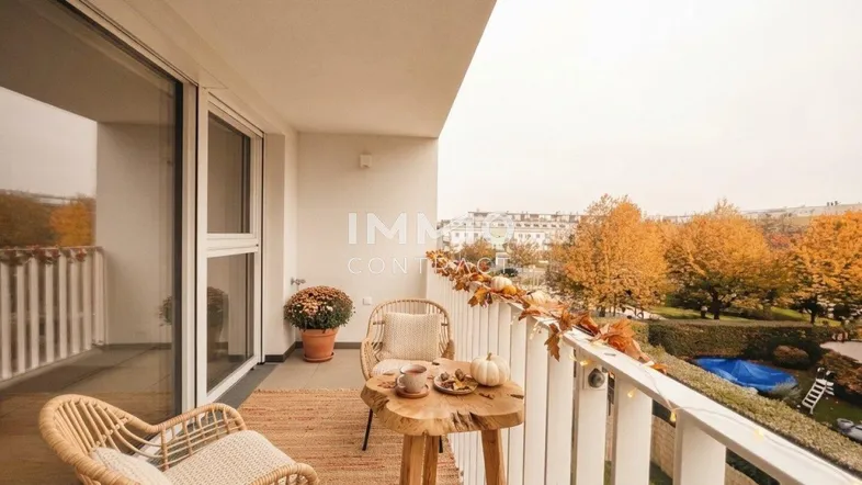 Gemütlicher Balkon mit Rattanmöbeln, herbstlicher Dekoration und Blick ins Grüne.