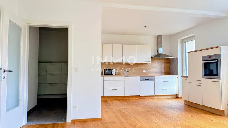 Helle, moderne Küche mit Holzboden und integrierten Geräten, angrenzend an einen praktischen Abstellraum.