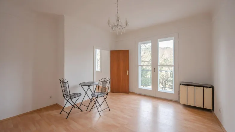 Helles Wohnzimmer mit Parkettboden, Stuckdecke und Zugang zu einem französischen Balkon.