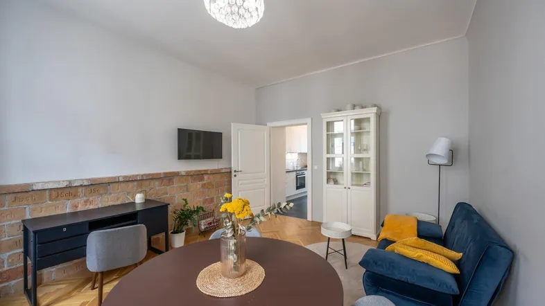 Helles Wohn- und Esszimmer mit Fischgrätparkett, moderner Einrichtung und freigelegter Ziegelwand.