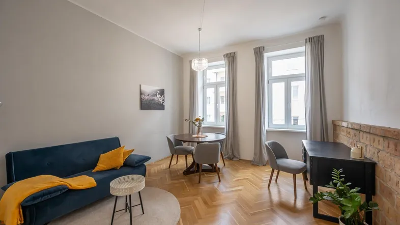 Helles Wohn- und Esszimmer mit Fischgrätparkett, bequemer Couch und einem Esstisch für gesellige Runden.