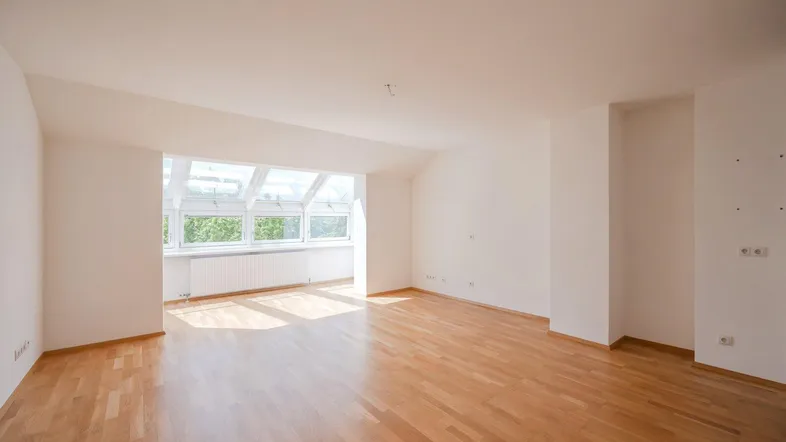 Helles Wohnzimmer mit Holzparkettboden und großen Dachfenstern, die viel Licht hereinlassen.