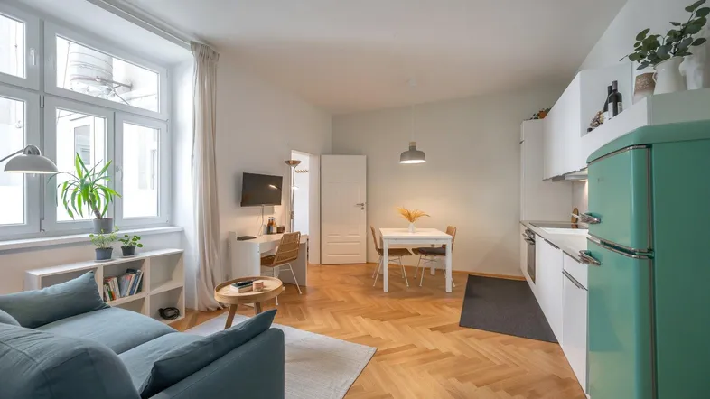 Helles, offenes Wohnzimmer mit integrierter Küche, Essbereich und Parkettboden.
