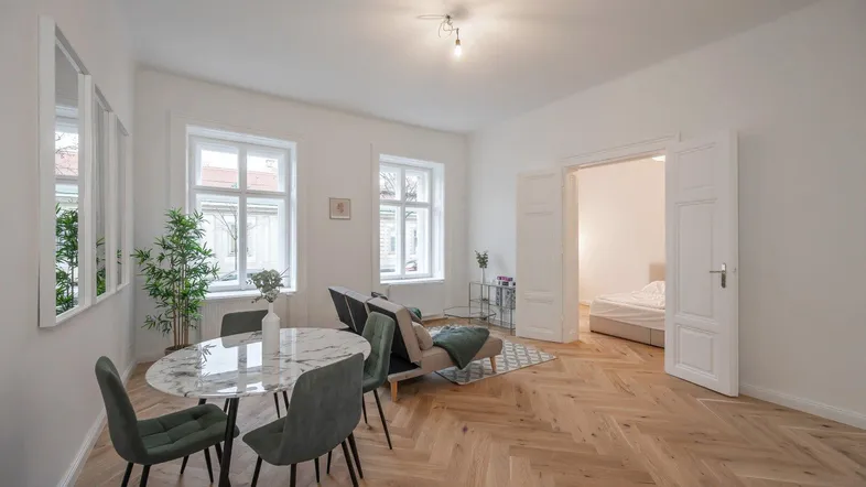 Helles Wohn- und Esszimmer mit Fischgrätparkett und modernem Mobiliar, offen gestaltet.