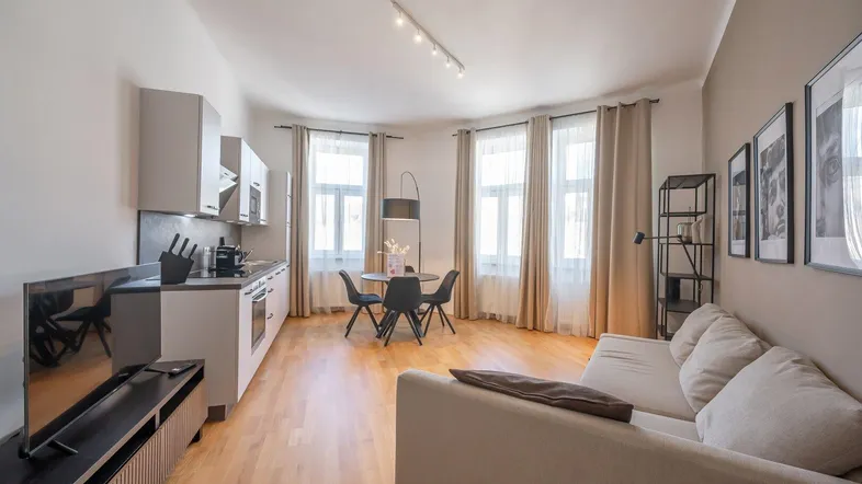 Moderner offener Wohnbereich mit integrierter Küche, Essplatz und hellem Parkettboden.