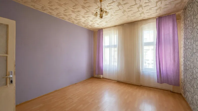 Helles Zimmer mit lila Wänden, gemusterter Decke und Holzboden, bereit zur individuellen Gestaltung.