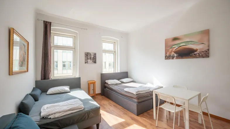 Helles Schlafzimmer mit zwei Betten, Esstisch und Holzfußboden.
