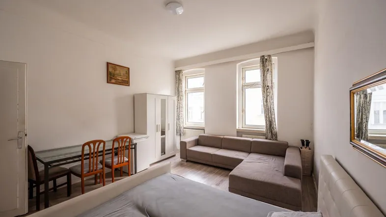 Helles Zimmer mit Schlafbereich, Sofa und Esstisch, ideal für ein Studio-Apartment.
