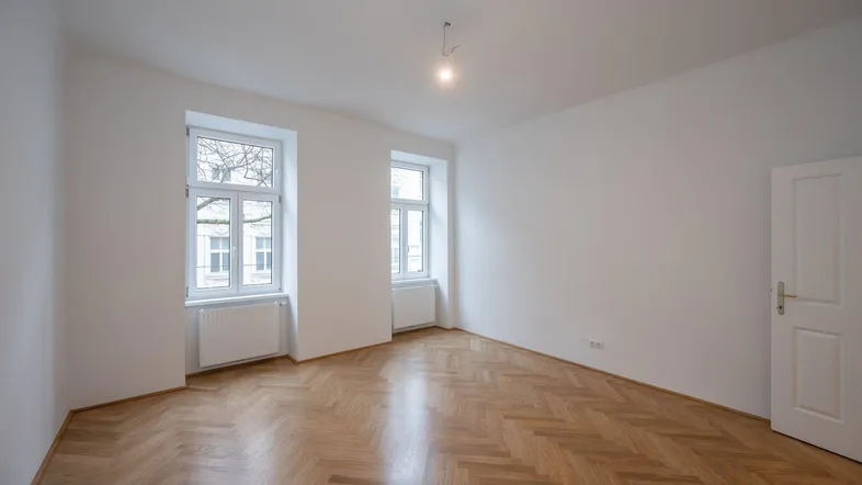 Helles Zimmer mit Fischgrätparkett und weißen Wänden, bereit für die individuelle Gestaltung.