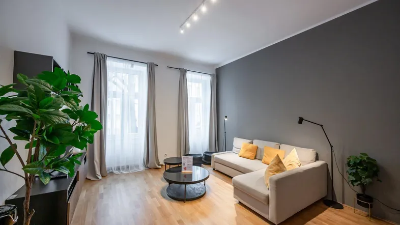 Helles Wohnzimmer mit modernem Sofa, Holzboden und grauer Akzentwand.