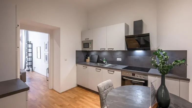 Moderne Küche mit hellen Schränken, Holzboden und einem kleinen Essbereich.