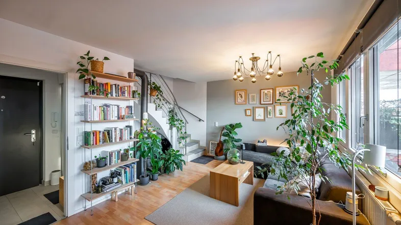 Helles Wohnzimmer mit Parkettboden, vielen Pflanzen und offenem Treppenaufgang.