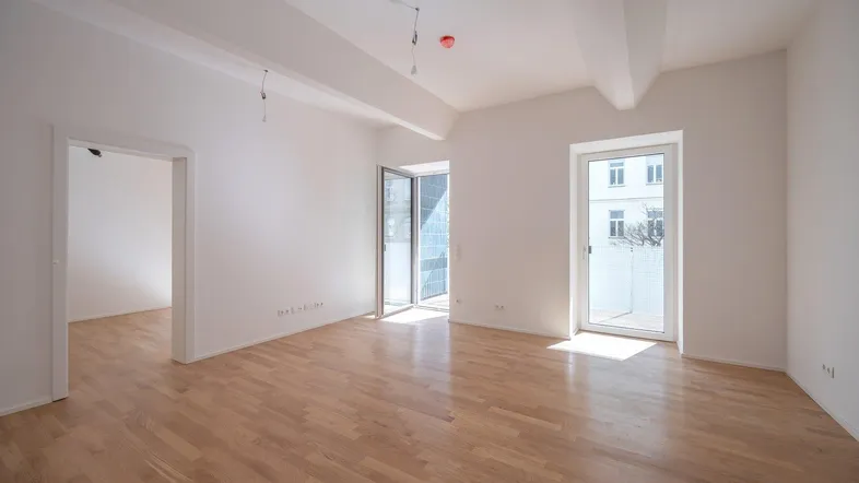 Helles, leeres Zimmer mit Parkettboden und Zugang zu einem Balkon, bereit zur individuellen Gestaltung.