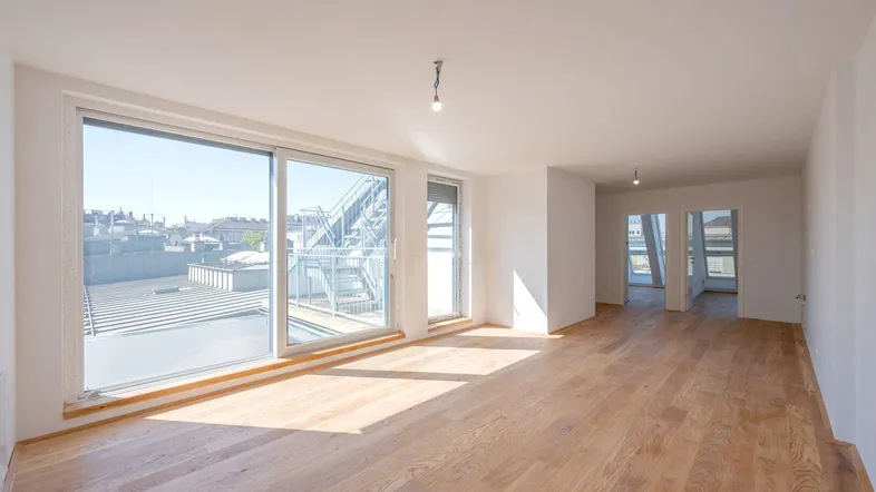 Helles, geräumiges Wohnzimmer mit Holzboden und Zugang zu einer Dachterrasse.