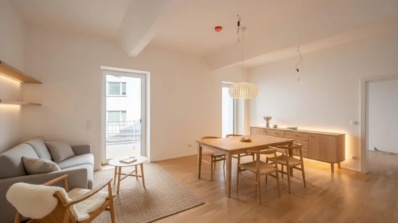 Heller Wohn- und Essbereich mit modernem Holzmobiliar, Parkettboden und Zugang zum Balkon.