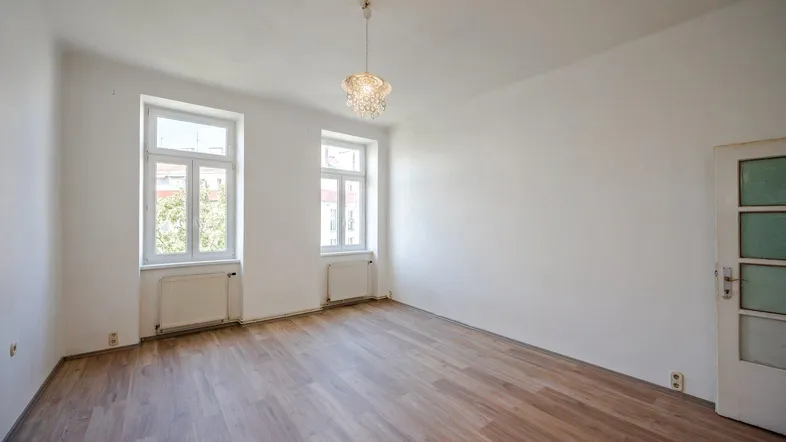 Helles Zimmer mit Holzboden, weißen Wänden und zwei Fenstern, bereit zur individuellen Gestaltung.