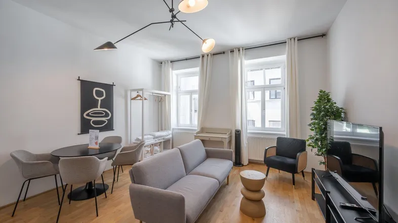 Helles Wohn- und Esszimmer mit modernem Mobiliar, Holzboden und großen Fenstern.