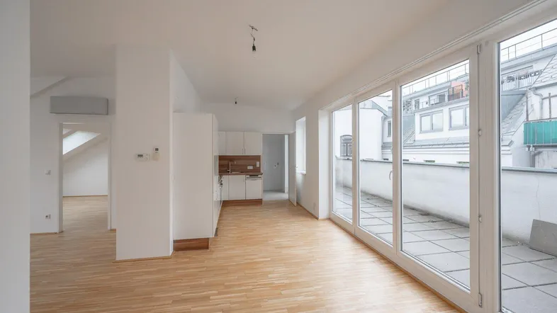 Helles, offenes Wohn-Esszimmer mit Parkettboden und Zugang zu einer großzügigen Terrasse.