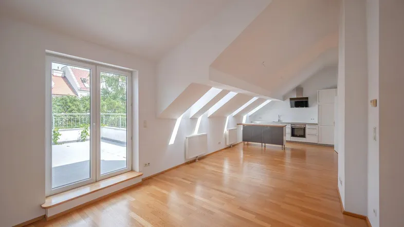 Heller offener Wohnbereich mit Holzboden, Dachschrägen und Zugang zu einer Terrasse.
