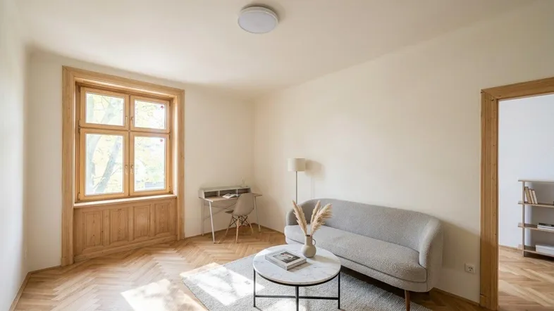 Helles Wohnzimmer mit Fischgrätparkett, modernem Sofa und einem Schreibtisch am Fenster.