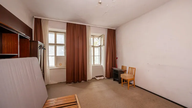 Geräumiges Zimmer mit Teppichboden, zwei Fenstern und braunen Vorhängen, derzeit als Schlafzimmer genutzt.
