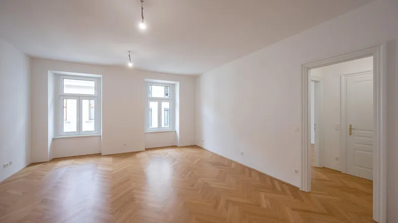Helles Zimmer mit Fischgrätparkett und weißen Wänden, bereit für individuelle Gestaltung.