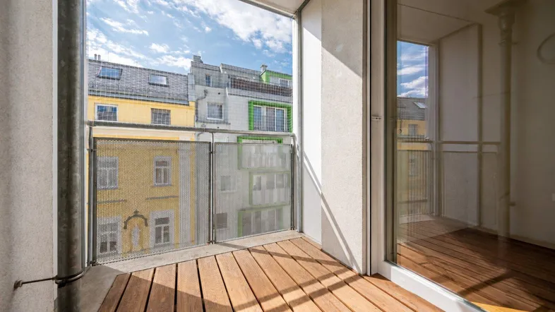Heller Balkon mit Holzboden und Blick auf die umliegenden Gebäude in der Stadt.