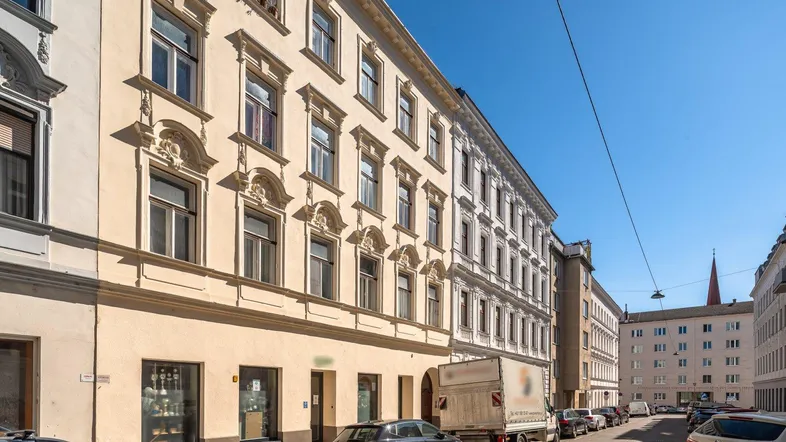 Historisches Mehrfamilienhaus mit reich verzierter Fassade an einer belebten Straße.