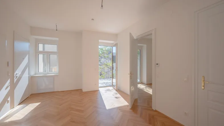 Helles Zimmer mit Fischgrätparkett und Zugang zu einem Balkon, ideal für Wohn- oder Schlafbereich.