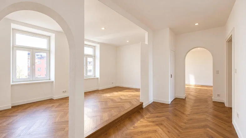 Helles, renoviertes Zimmer mit Fischgrätparkett und Rundbögen, bereit für die Einrichtung.