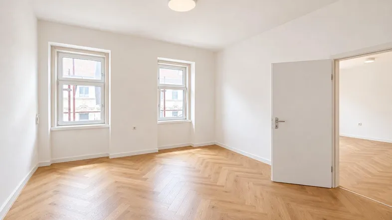 Helles Zimmer mit modernem Fischgrätparkett und zwei großen Fenstern, frisch renoviert.