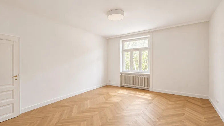 Heller Raum mit neuem Fischgrätparkettboden, weißen Wänden und einem großen Fenster.