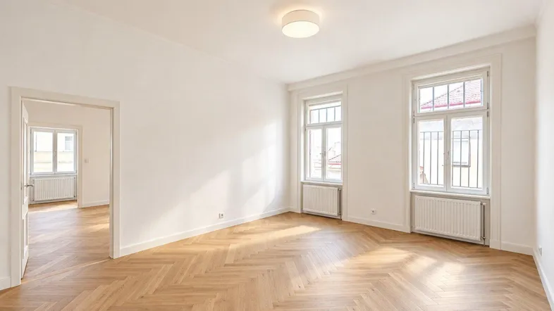 Helles Wohnzimmer mit Fischgrätparkett, hohen Decken und zwei großen Fenstern.