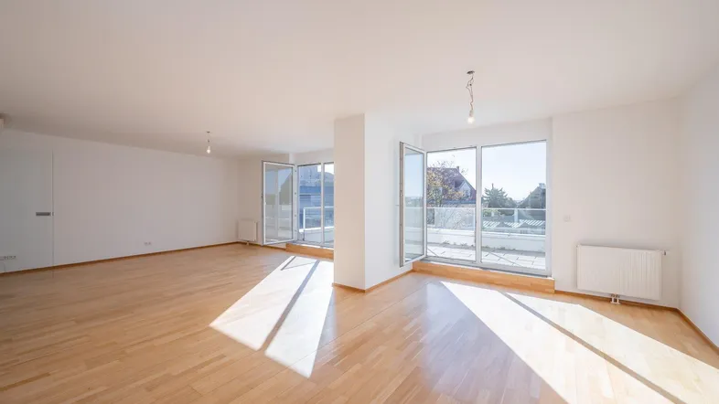 Helles und geräumiges Wohnzimmer mit Parkettboden und Zugang zu einer großen Terrasse.