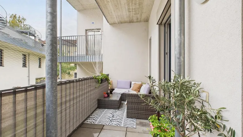 Möblierter Balkon mit Fliesenboden und Sichtschutz, ideal für entspannte Stunden im Freien.