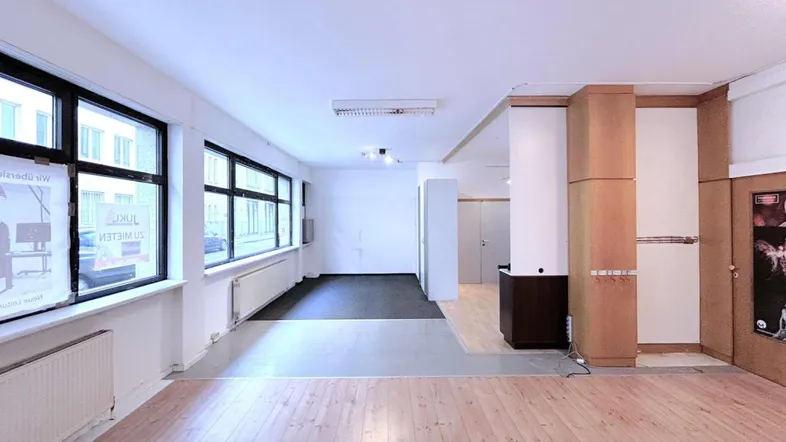 Geräumiger Innenraum mit Holzboden, großen Fenstern und verschiedenen Bodenbelägen, ideal für Büro oder Gewerbe.