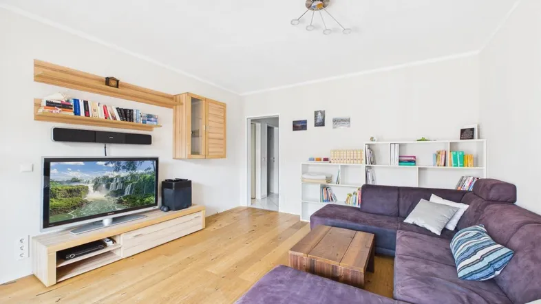 Helles Wohnzimmer mit Eichenparkett, modernem TV-Möbel und lila Ecksofa.