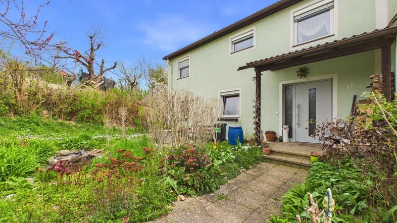 Eingangsbereich eines Hauses mit grün gestrichener Fassade und einem kleinen Vorgarten.