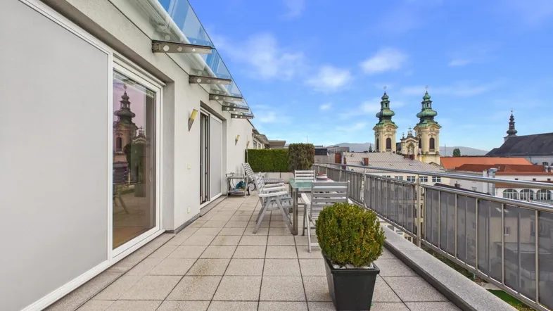 Große Dachterrasse mit Sitzgelegenheiten und weitem Blick über die Stadt mit Kirchtürmen.