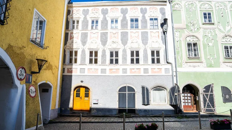 Historische Fassade eines Gebäudes mit kunstvollen Verzierungen und einer leuchtend gelben Eingangstür.