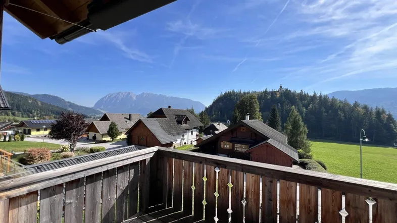 Holzbalkon mit weitem Blick über die ländliche Umgebung und ferne Berge.