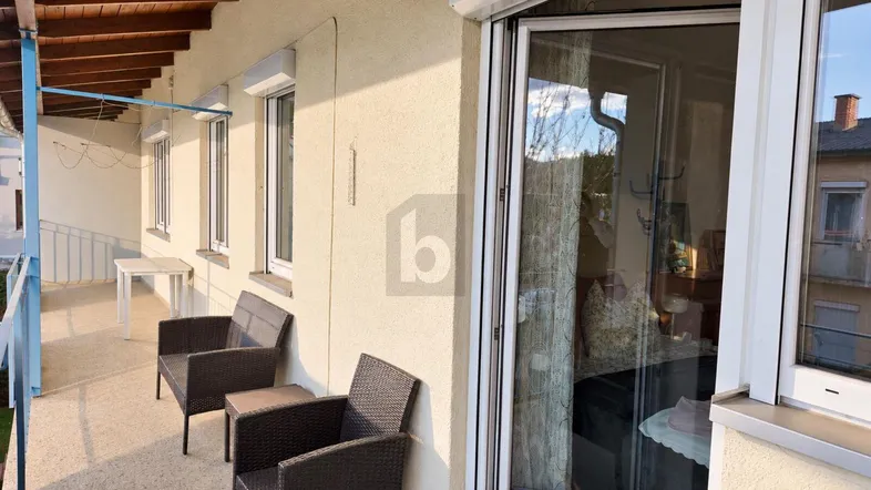Möblierter Balkon mit Holzdach, Rollläden und Zugang zum Innenbereich, ideal für entspannte Stunden.