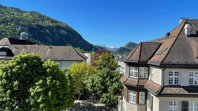 Panoramablick auf die umliegenden Berge und historische Gebäude der Stadt.