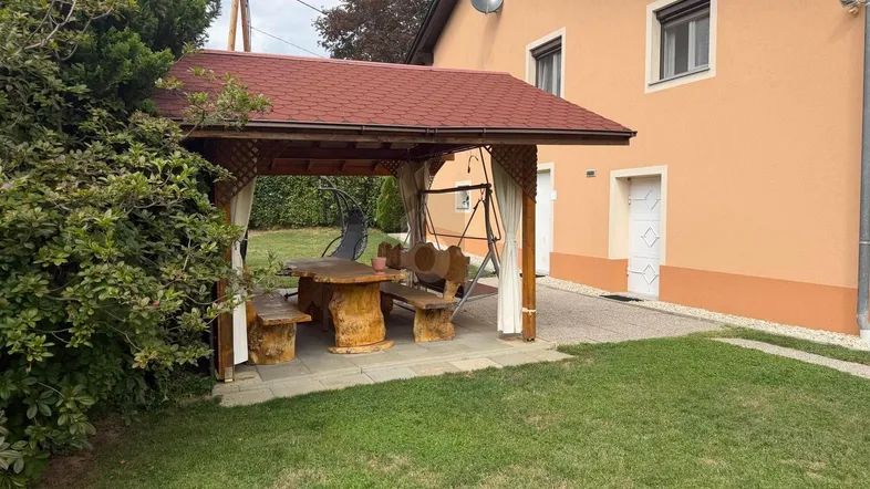 Gemütlicher Gartenbereich mit überdachtem Sitzplatz, Rasenfläche und Blick auf das Wohnhaus.