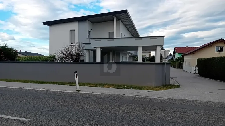 Modernes Einfamilienhaus mit klarer Architektur, weißer Fassade und überdachtem Eingangsbereich.