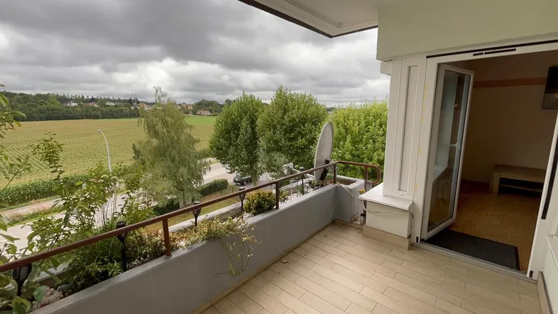 Geräumiger Balkon mit Holzboden und weitem Blick über Felder und Bäume.