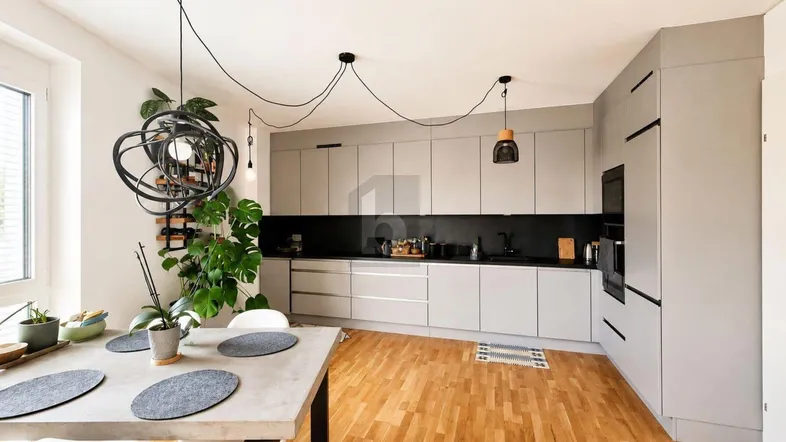 Moderne offene Küche mit grauen Schränken, Holzboden und integriertem Essbereich.