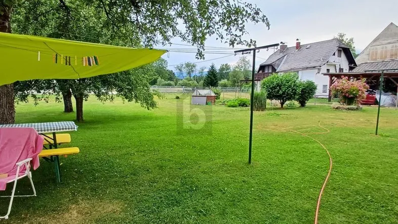 Großer grüner Garten mit Rasenfläche, Bäumen und einem schattigen Sitzbereich im Freien.