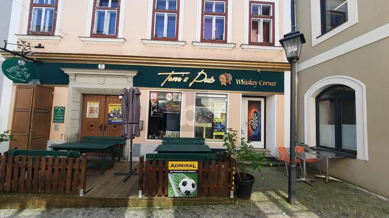 Außenansicht eines historischen Gebäudes mit einem Pub und Tischen im Freien.