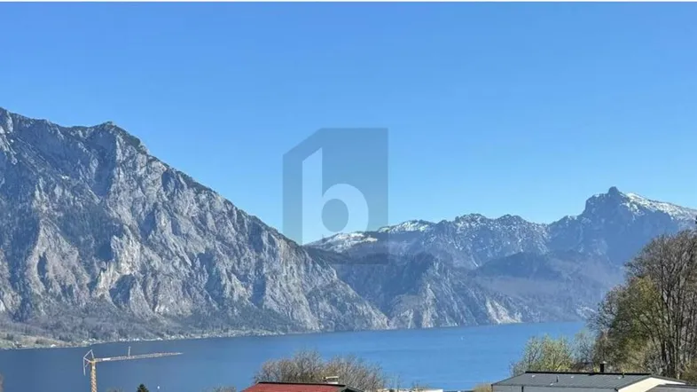 Panoramablick auf majestätische Berge und einen ruhigen See unter klarem blauem Himmel.
